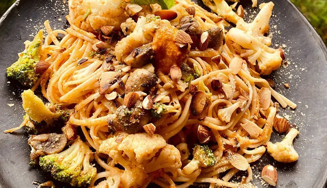 A close up of a plate of pasta with broccoli and mushrooms.