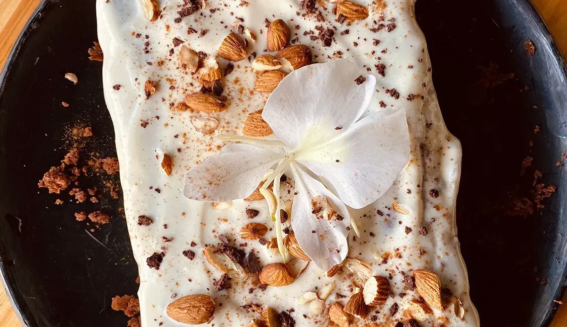 A piece of cake with a flower on top of it on a plate.