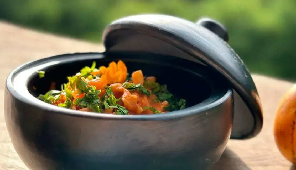 A bowl of food with a lid is on a table.