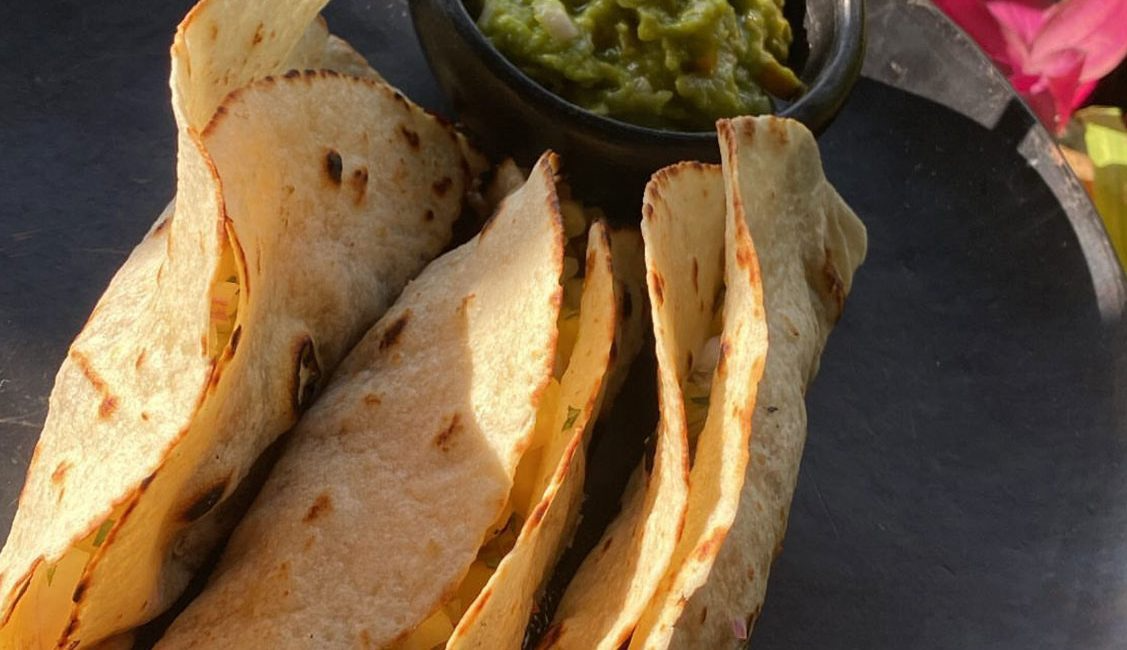 A black plate topped with tortilla chips and guacamole.
