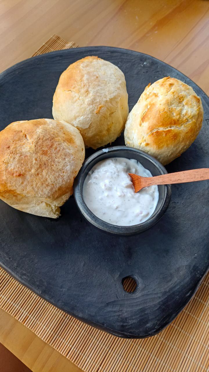 A black plate topped with three biscuits and a bowl of dipping sauce.