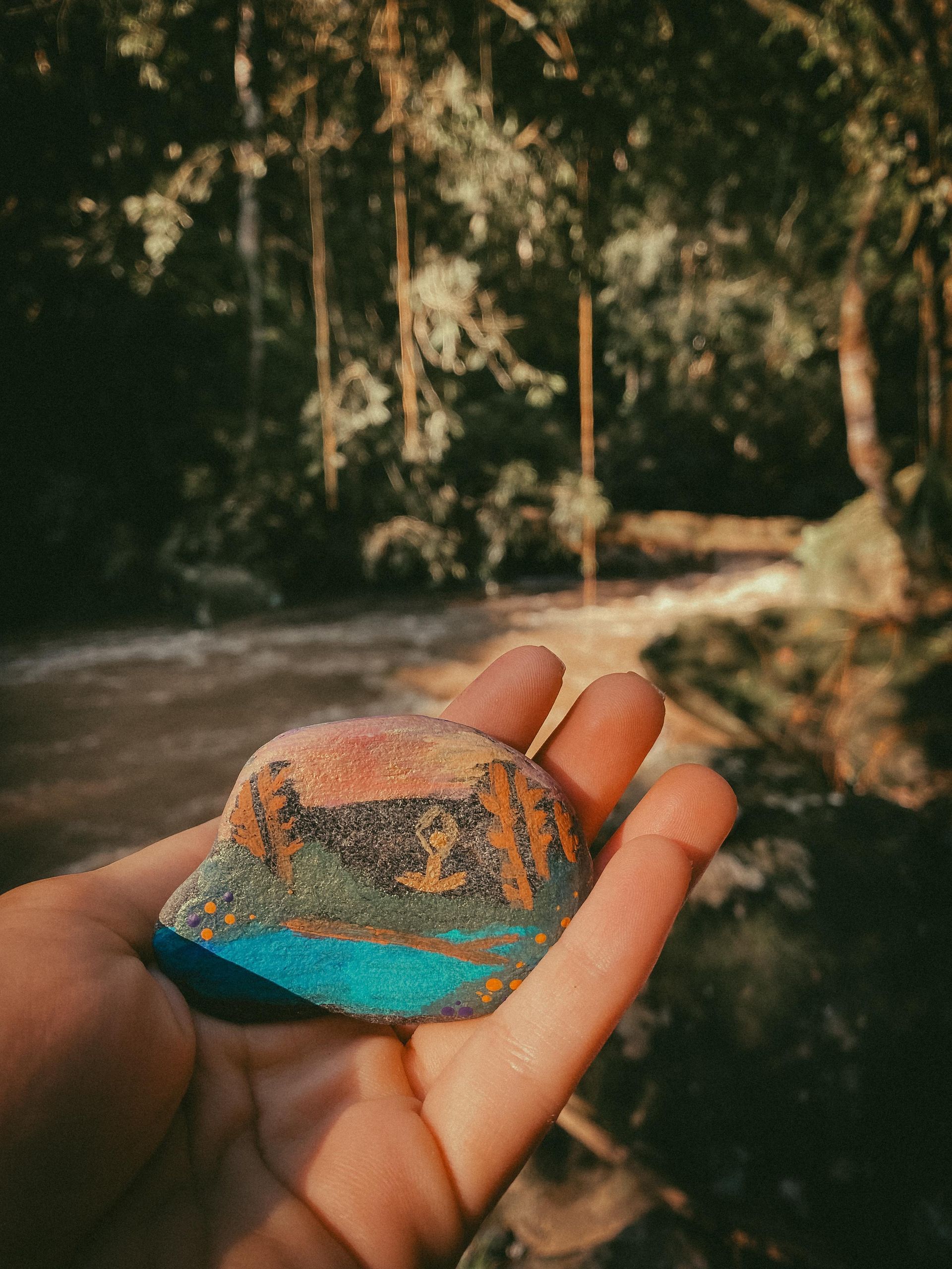 A person is holding a rock in their hand in front of a river.