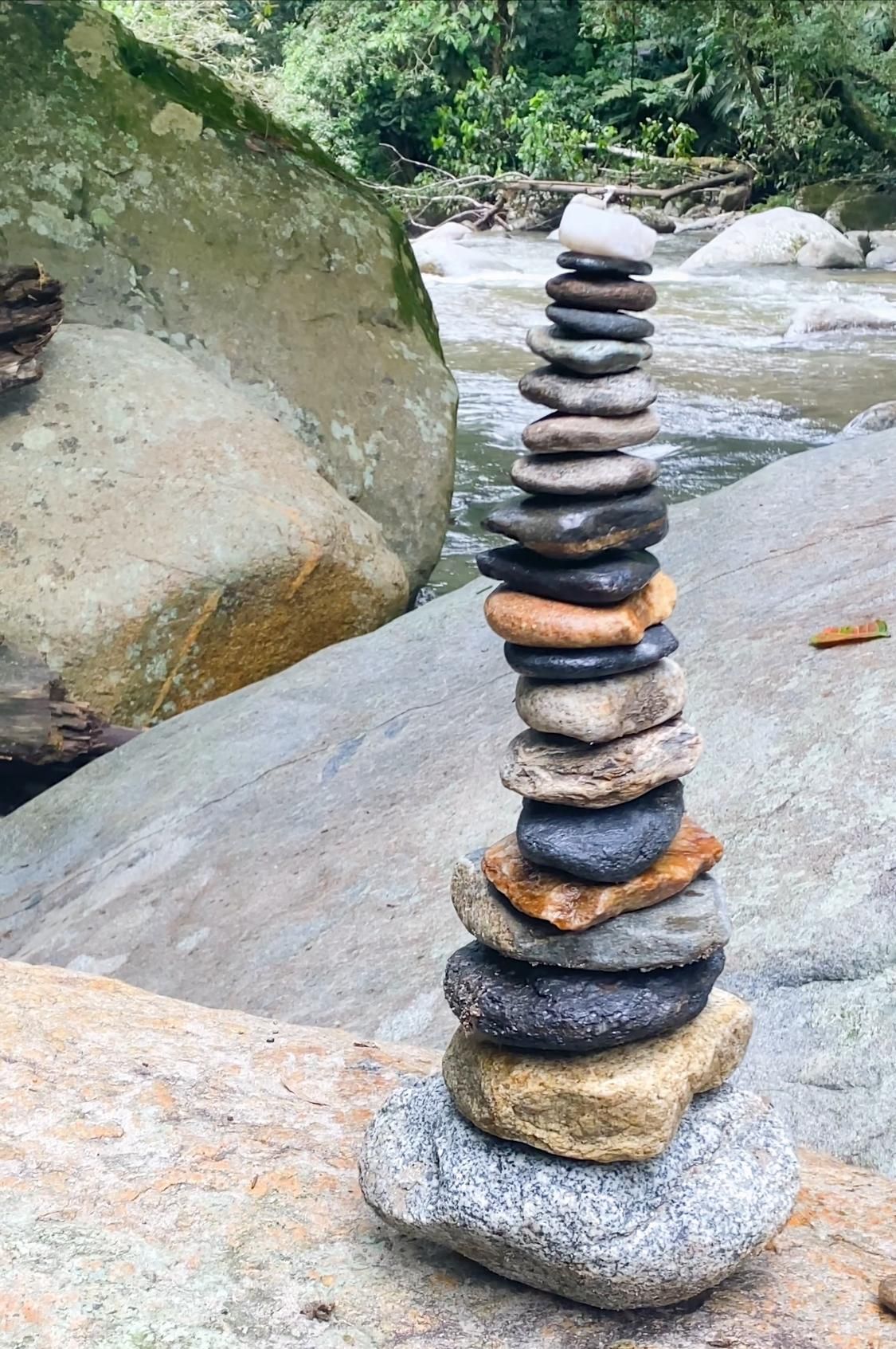 A stack of rocks sitting on top of a rock next to a river.