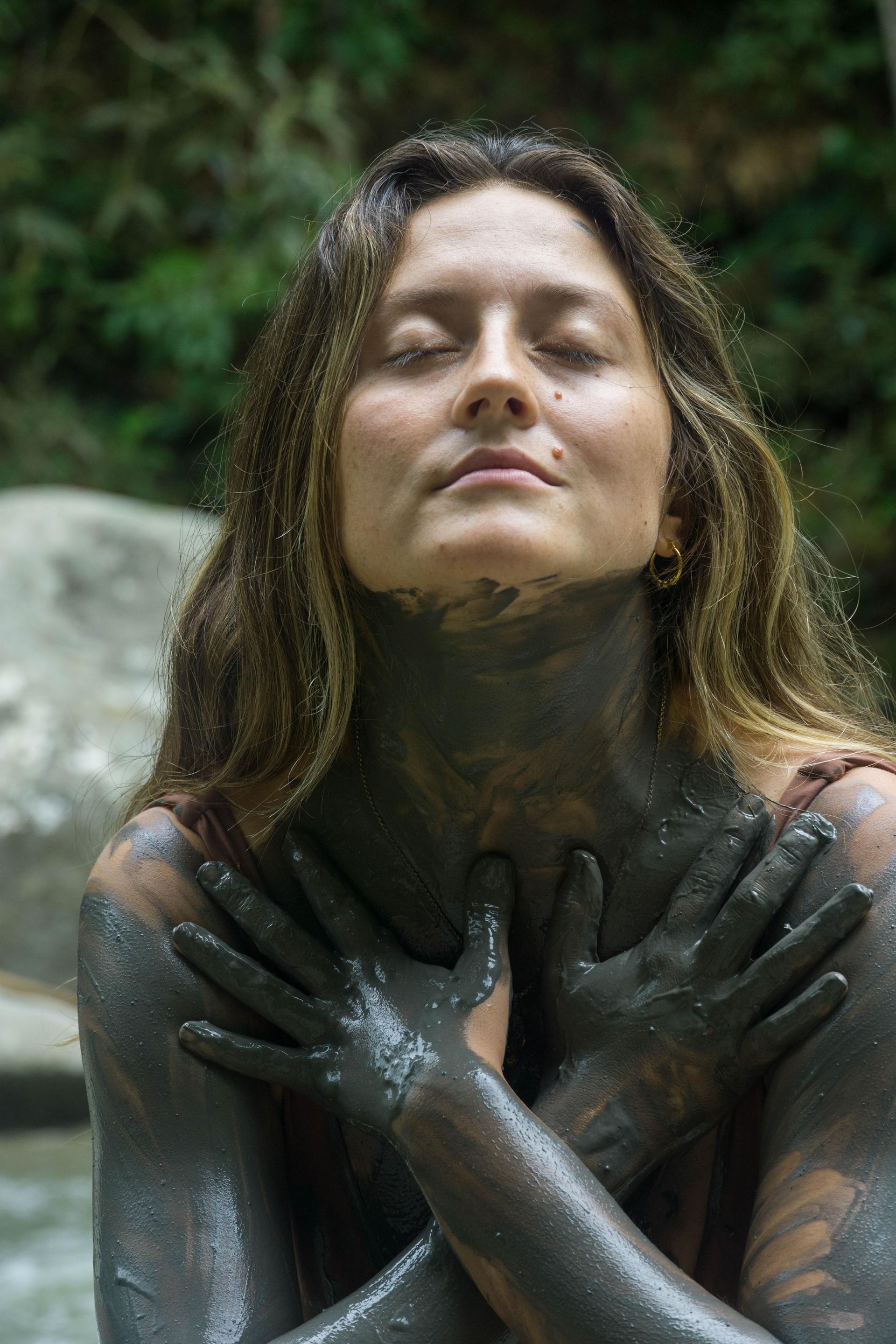 A woman is covered in mud and has her eyes closed.