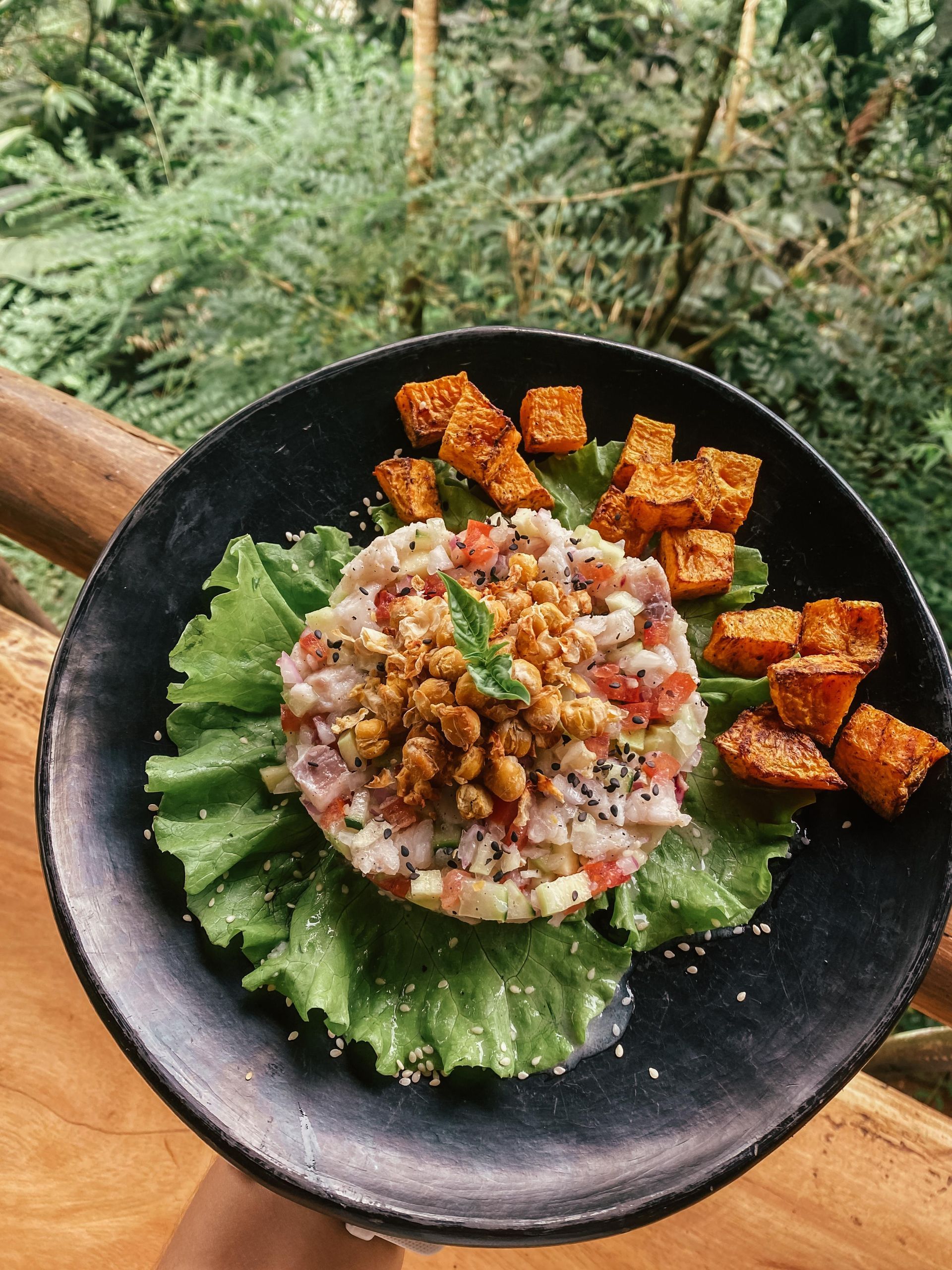 A person is holding a plate of food with lettuce and potatoes.