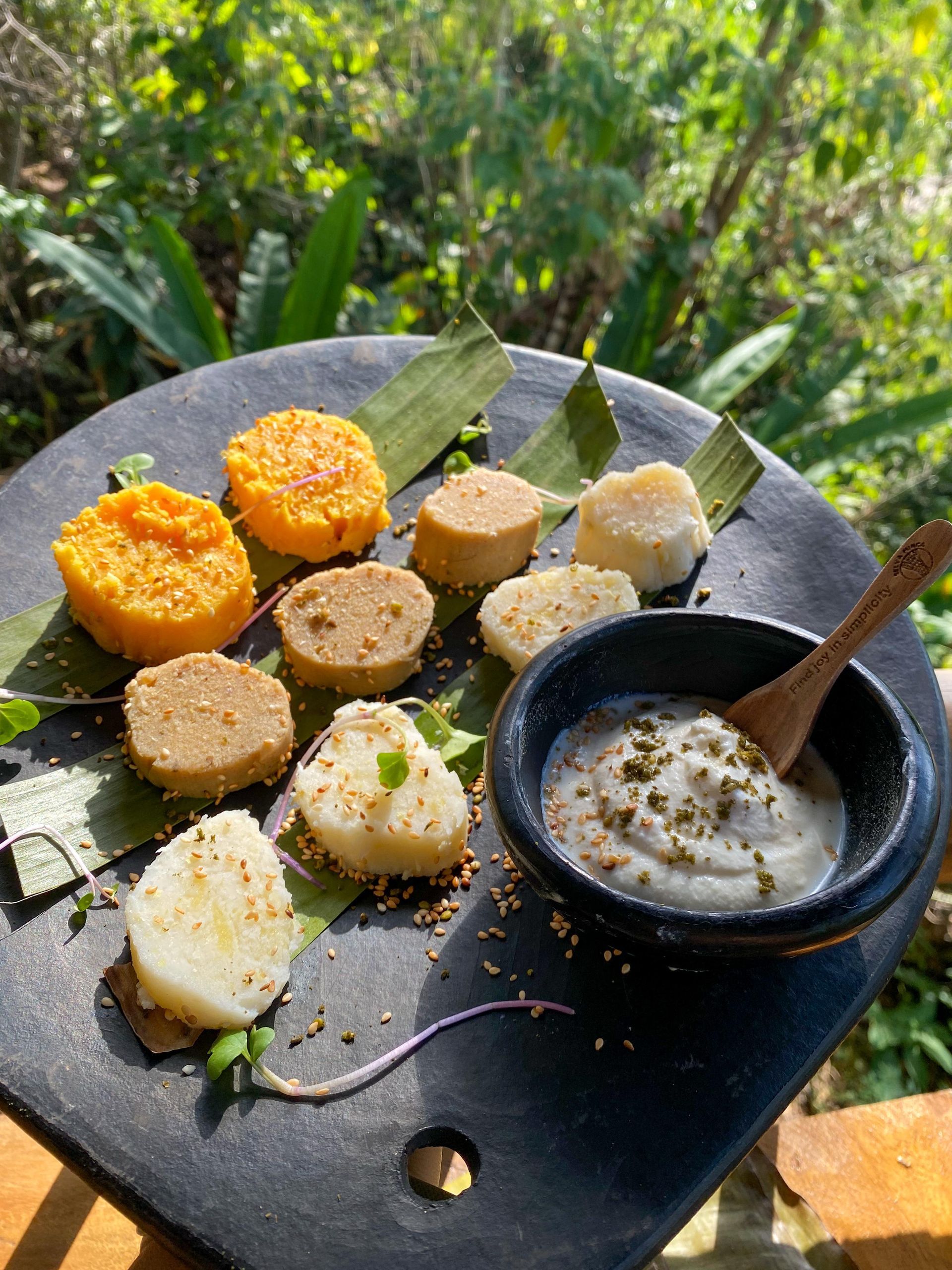 A plate of food with a bowl of sauce and a spoon on a table.