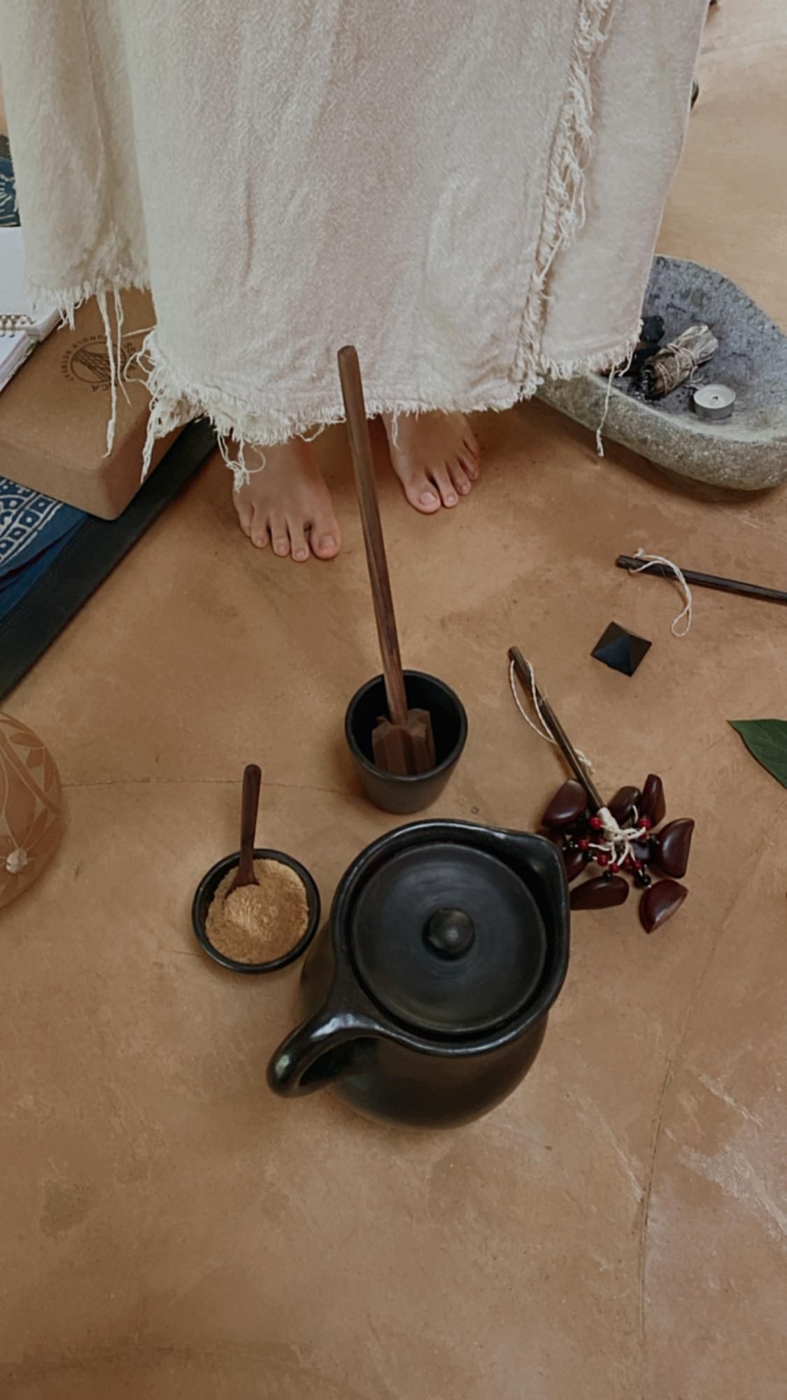 A person is standing next to a teapot on the floor.