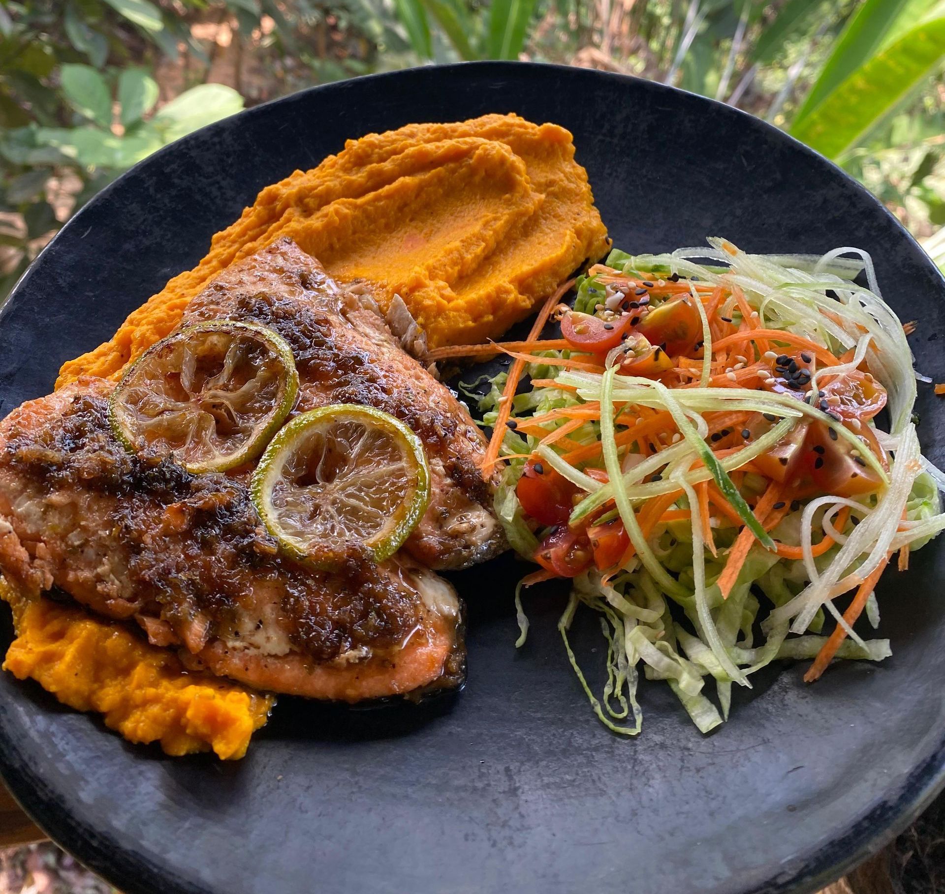 A black plate topped with meat and vegetables