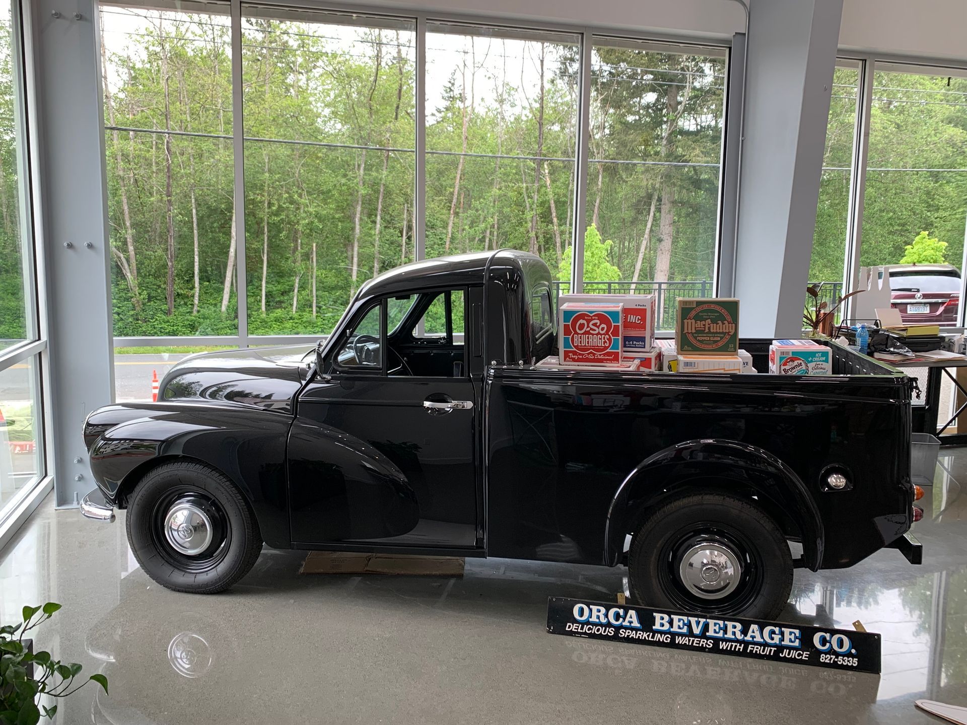 A black truck is parked in a room with a sign that says orca beverage co.