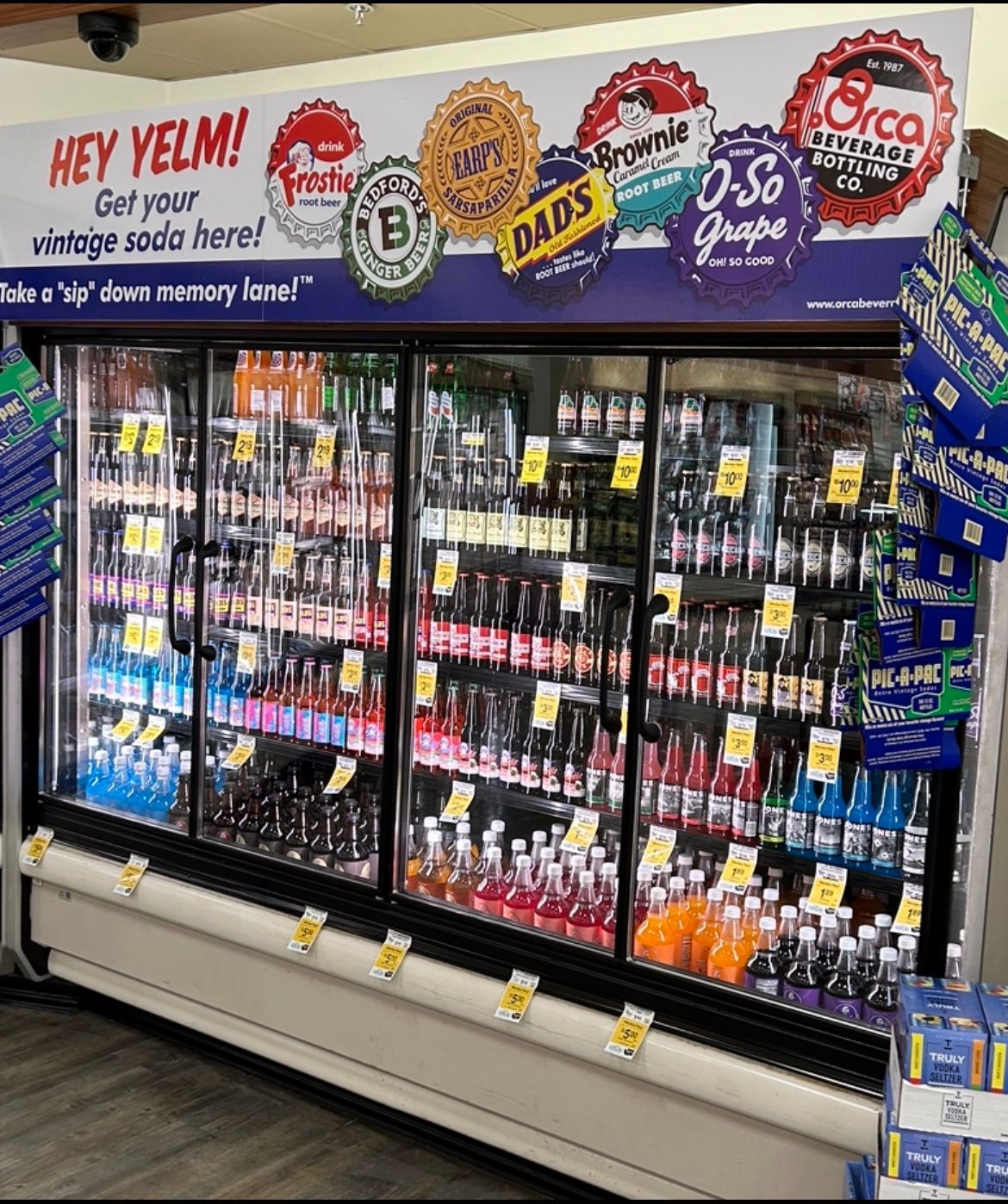 A refrigerator filled with bottles of soda and a sign that says hey yelm