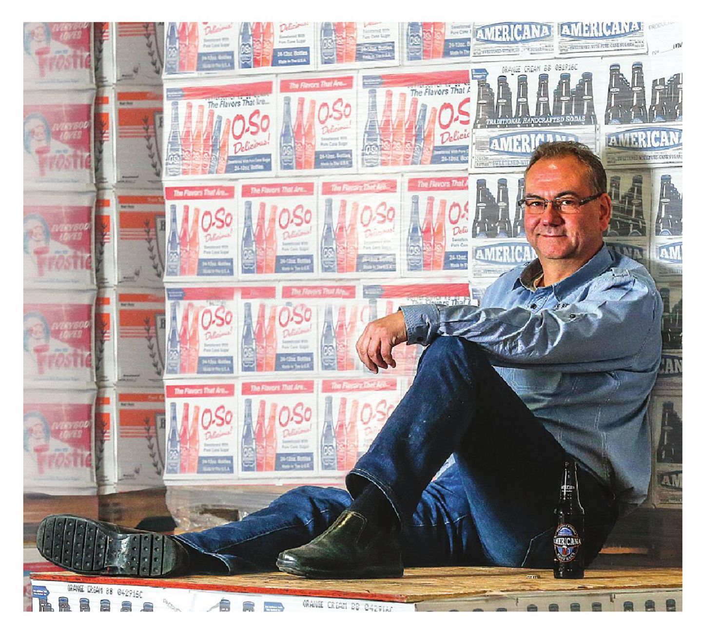 A man sits on a table with a bottle of beer