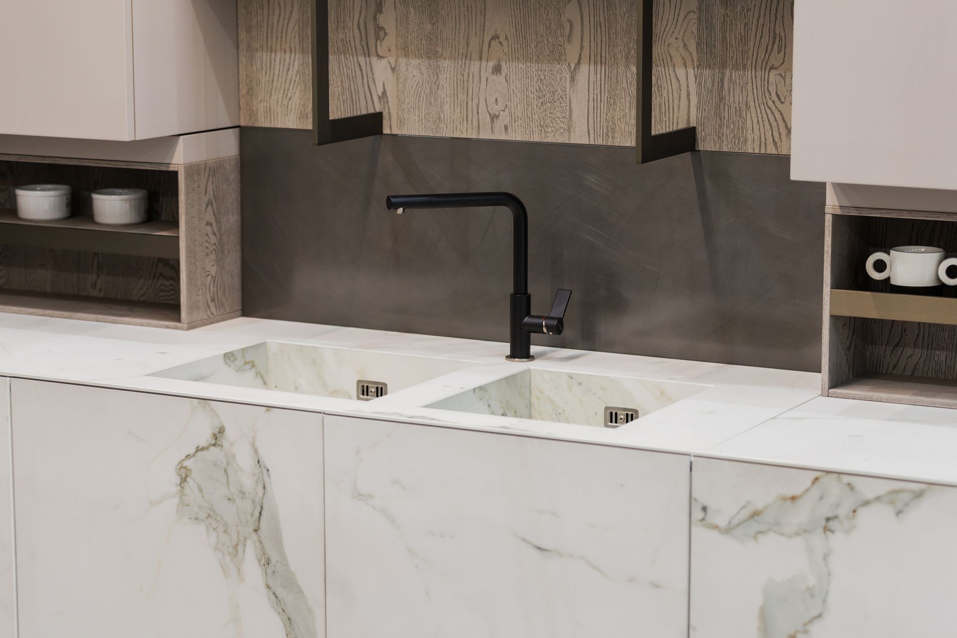 Modern kitchen sink with marble countertops and black faucet.