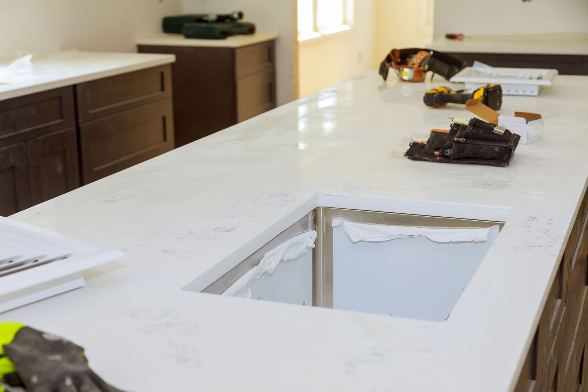 A kitchen countertop with a sink cutout, under construction with tools and cabinets.
