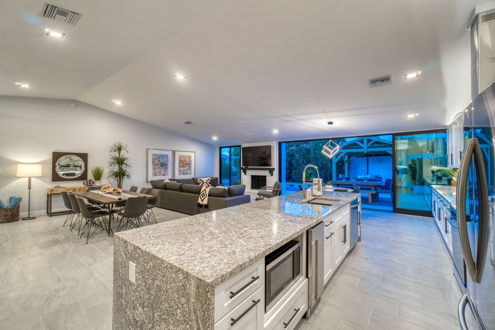Open-concept living space with a granite kitchen island, dining area, and sliding doors to an outdoor patio.