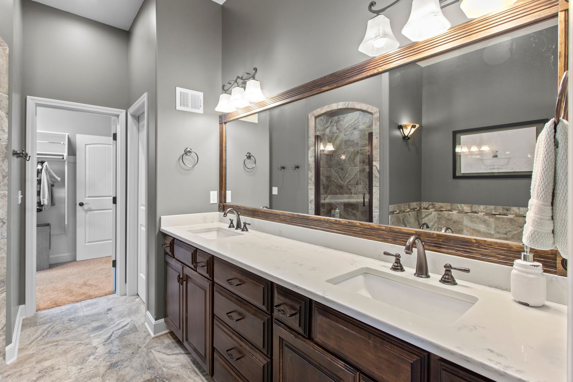 Bathroom with double vanity, dark wood cabinets, large mirror, and gray walls.