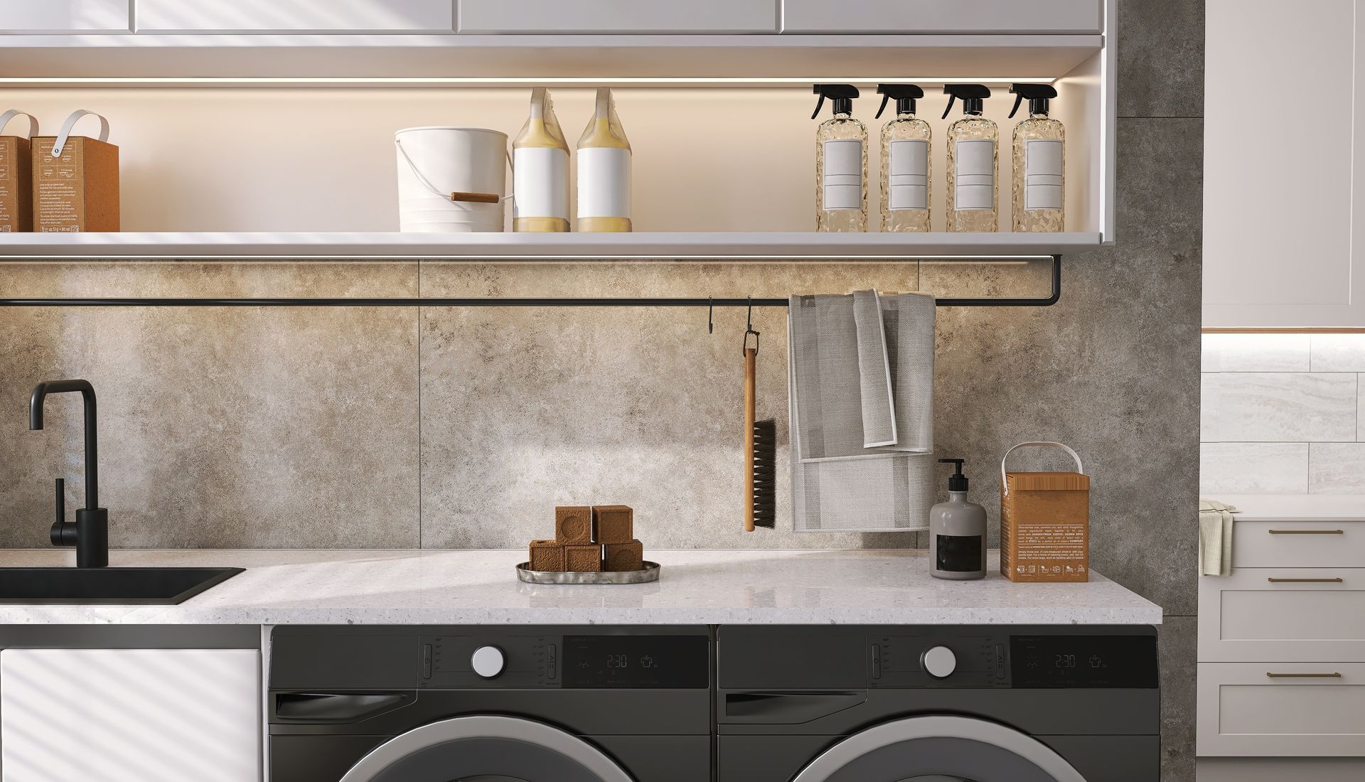 Laundry room with black washer/dryer, white countertop, and gray and white cabinets.
