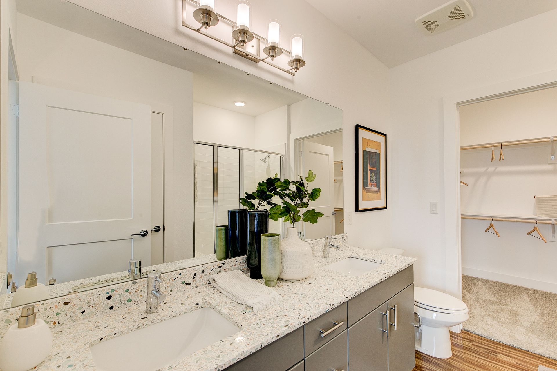 A bathroom with two sinks , a toilet and a large mirror.