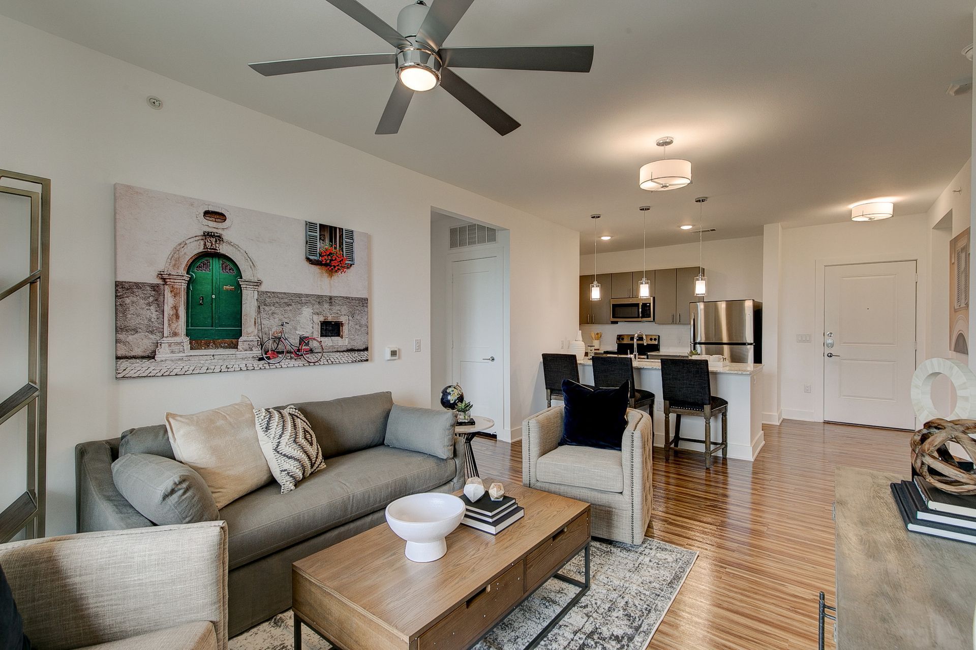 A living room with a couch , chairs , coffee table and ceiling fan.