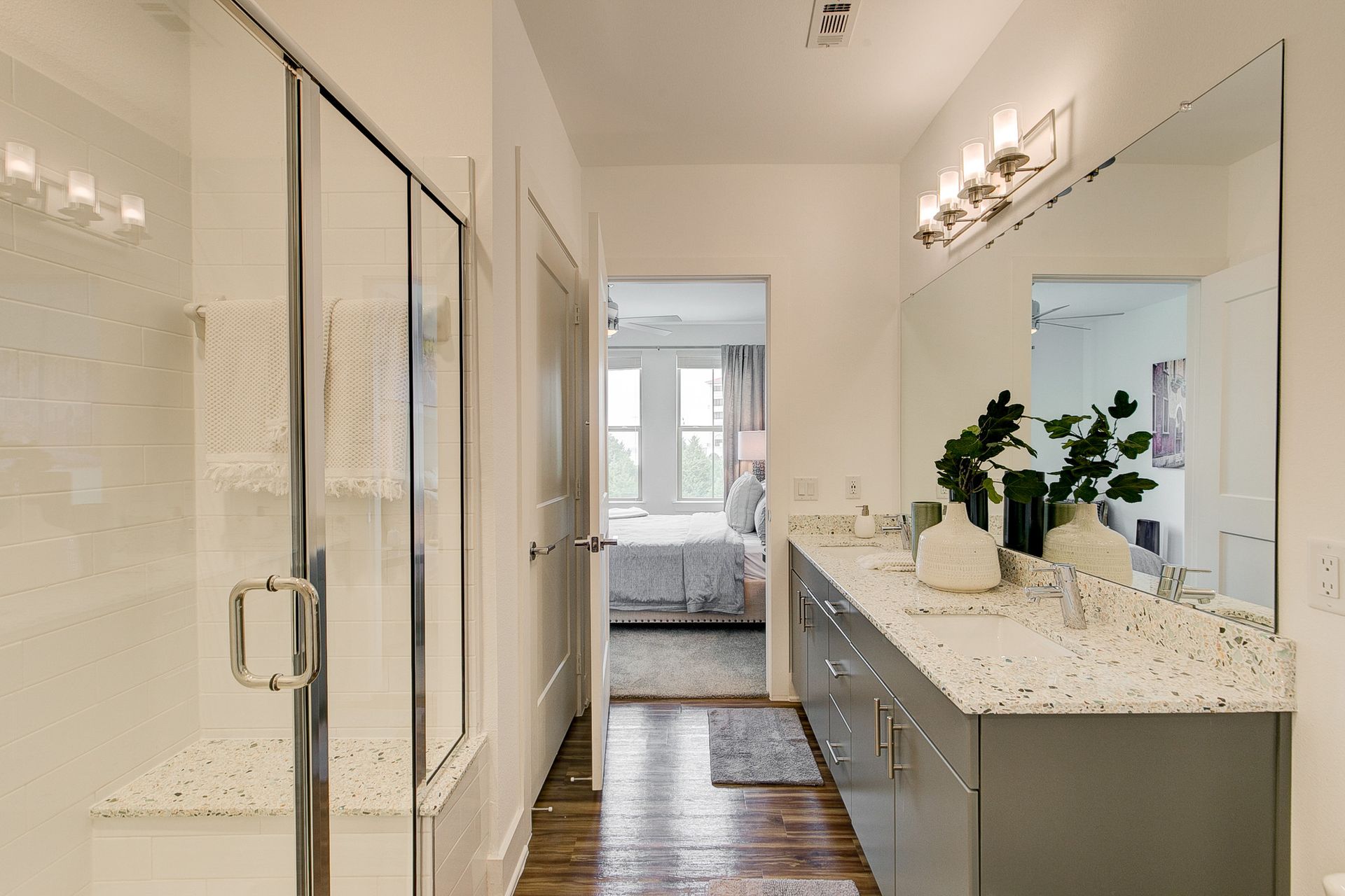 A bathroom with two sinks , a walk in shower and a large mirror.