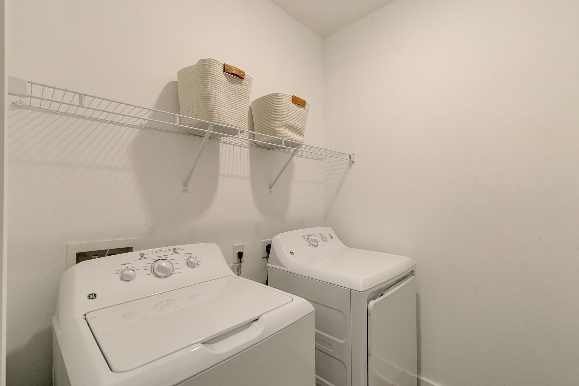 A laundry room with two white washers and dryers.