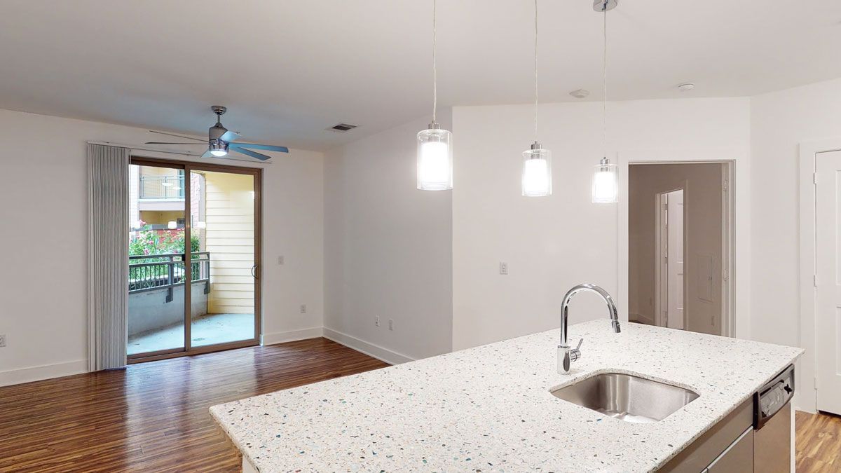 A kitchen with a sink and a sliding glass door.