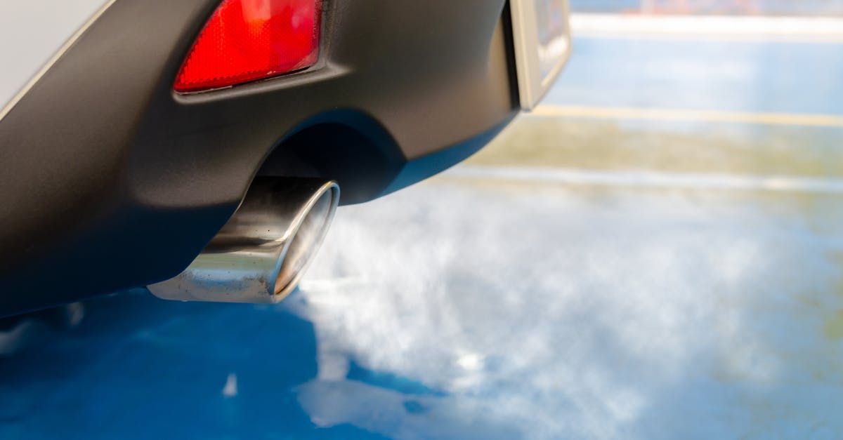 A close up of a car exhaust pipe with smoke coming out of it.  | Grooms Motors & Automotive