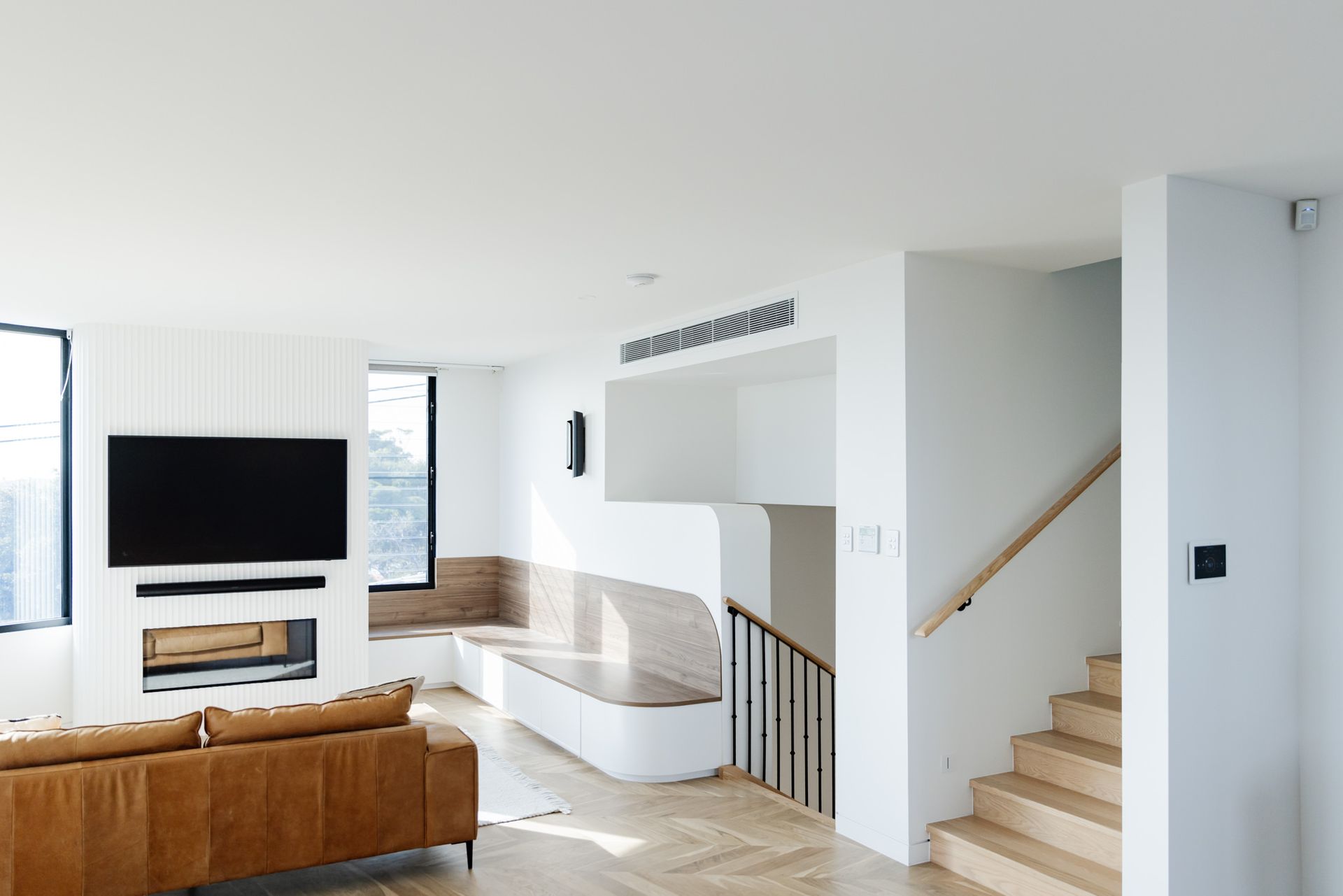 Modern living room featuring bar grille ducted air conditioning and smart home touch panel, designed