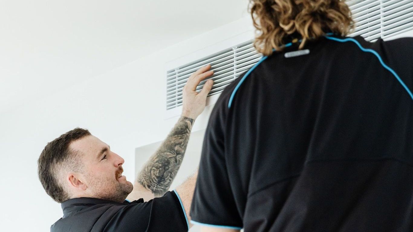 Image of Liam and Dane from Win Air and Electrical standing in front of the Win Air and electrical work ute 