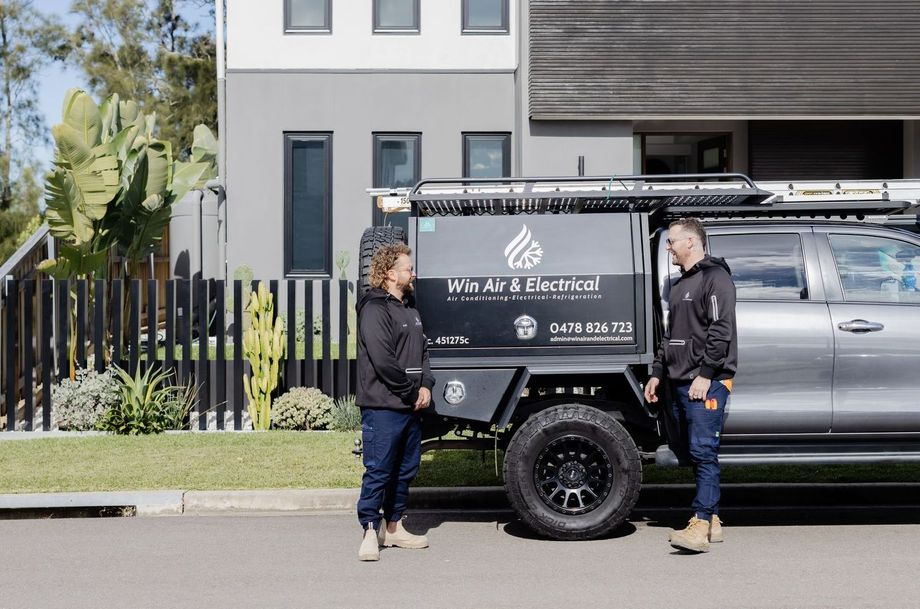 Two Win Air & Electrical team members standing in-front of work vehicle.