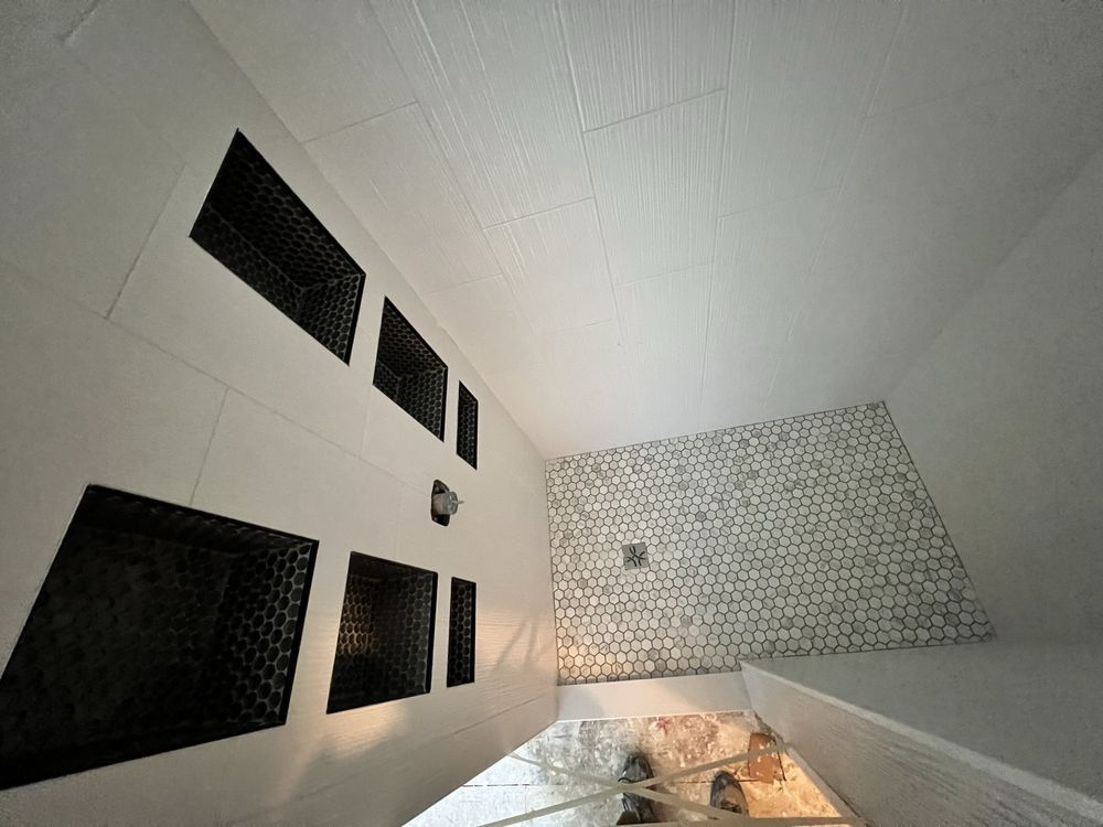 Interior view of a white room with dark vent-like rectangular openings and a textured tile wall.