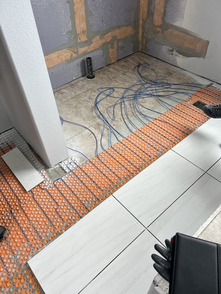 Bathroom floor construction in progress; tiles, heating mat, and wires visible.