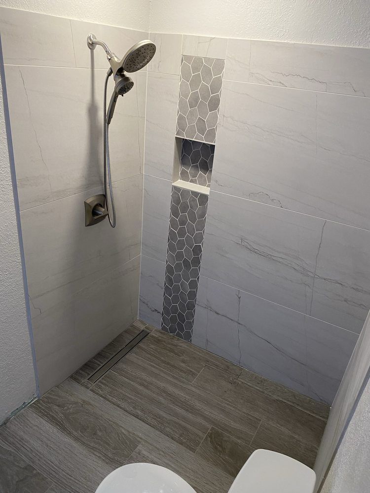 Modern bathroom with white and gray tile, showerhead, and a narrow, tiled shelf.