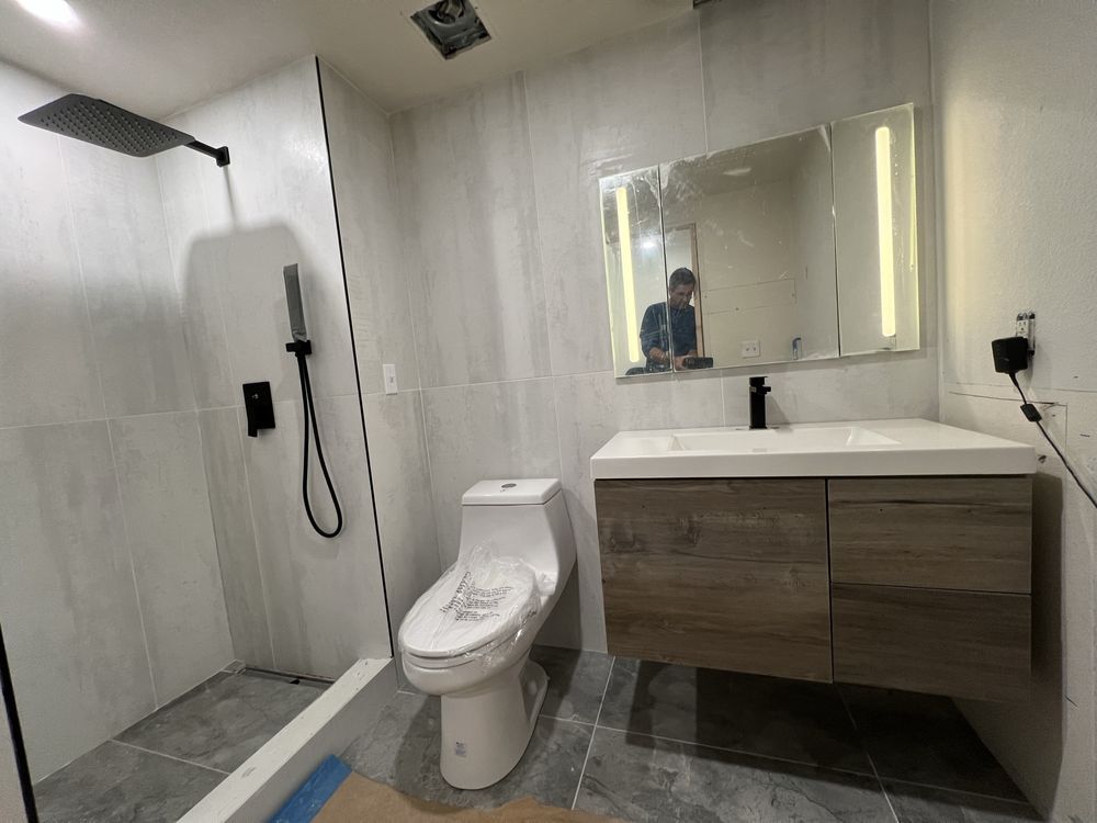 Modern bathroom with black shower fixtures, floating vanity, and white toilet.