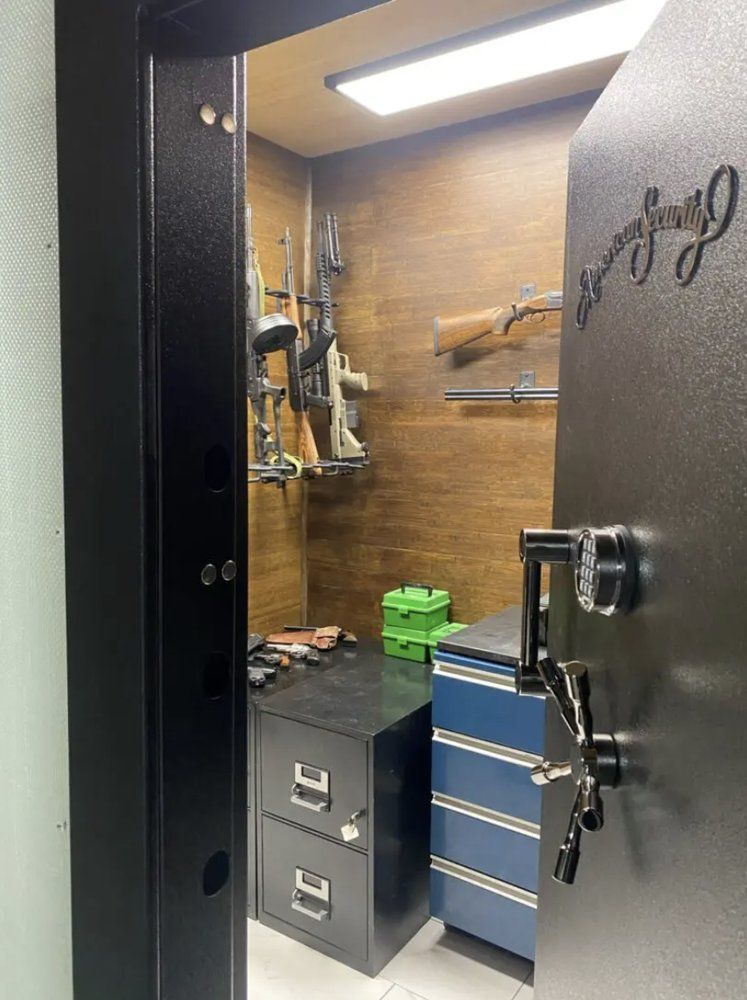 A gun safe interior with rifles and handguns mounted on the wall, and file cabinets.