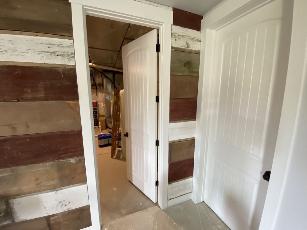 White doors with trim in a room with wood-paneled walls; one door is open.