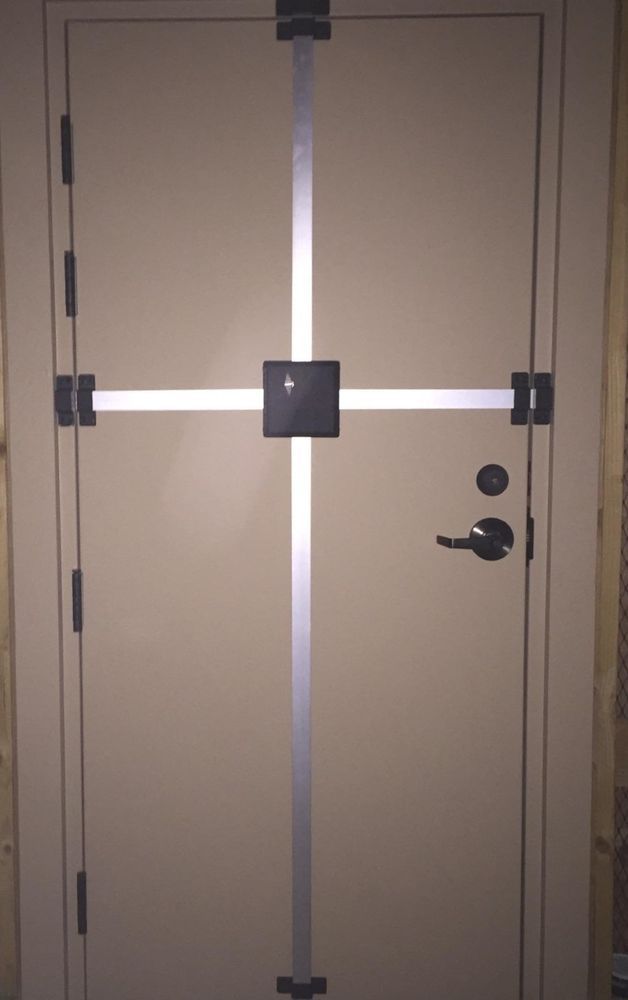 Tan door with a security bar system installed; a black lock and handle are visible.