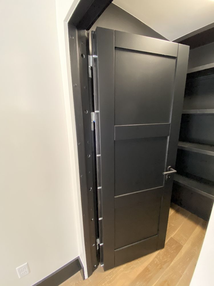 Black door, with visible hinges, partially open into a built-in shelving unit.