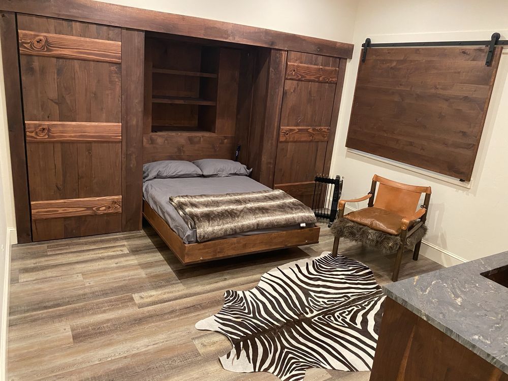 Bedroom with wooden sliding doors, floating bed, zebra rug, and armchair.