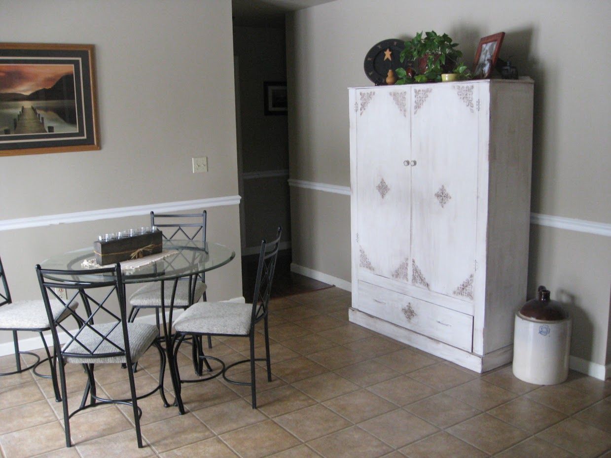 A dining room with a table and chairs and a white cabinet