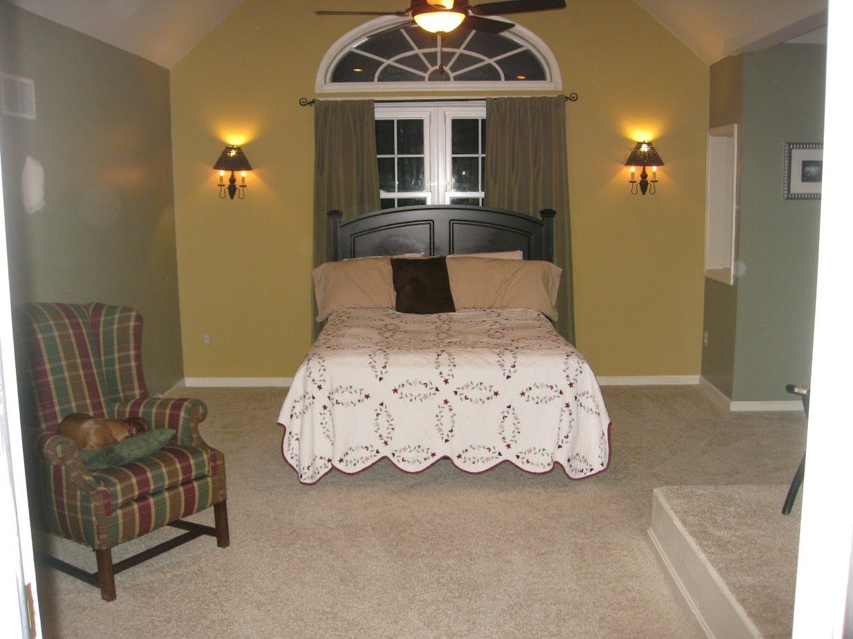 A bedroom with a large bed and a chair