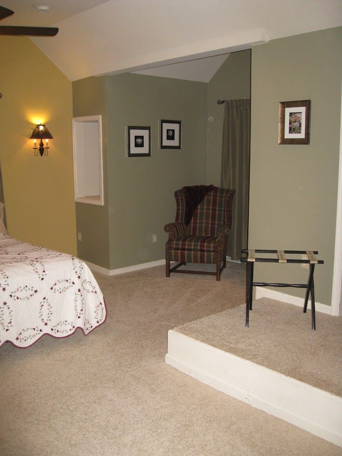 A bedroom with a bed a chair and a picture on the wall