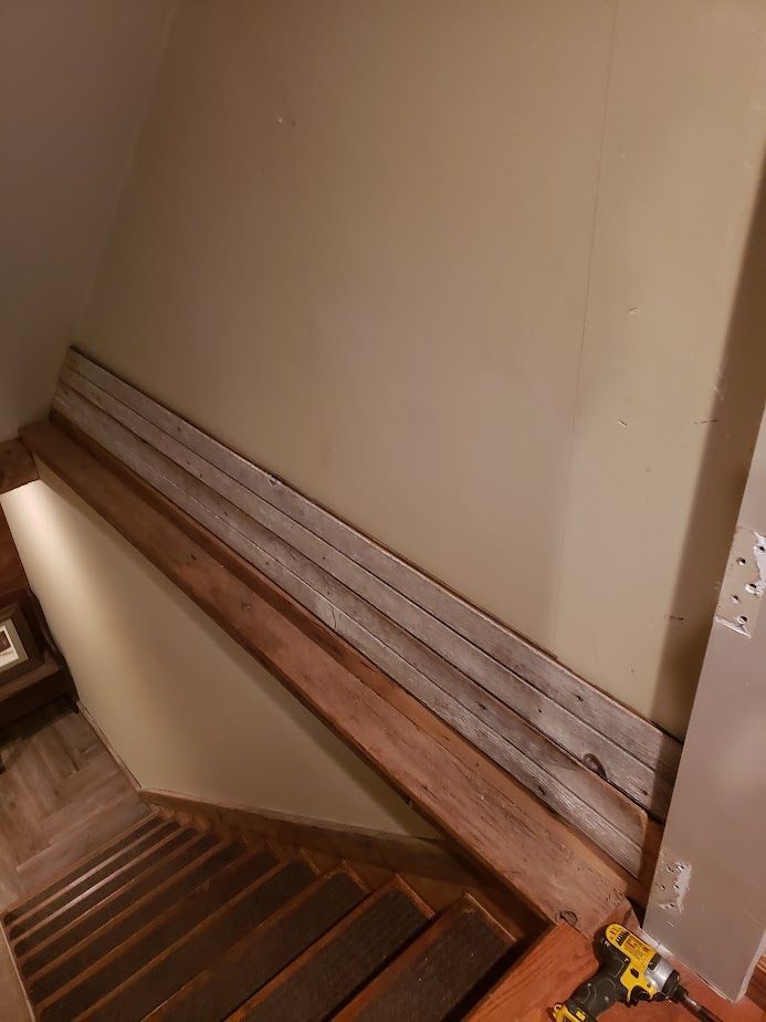 A wooden railing is being installed on the side of a staircase.