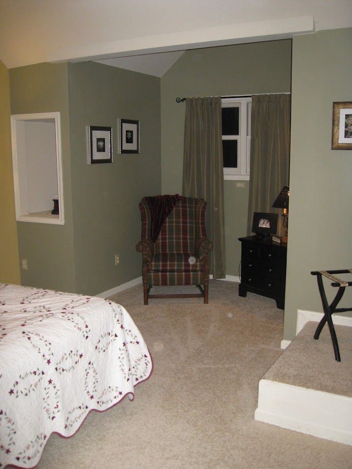 A bedroom with a bed a chair and a nightstand