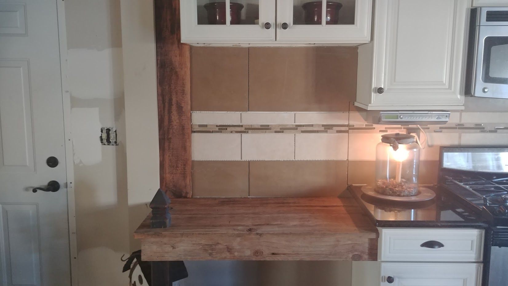 A kitchen with white cabinets , a stove and a microwave.