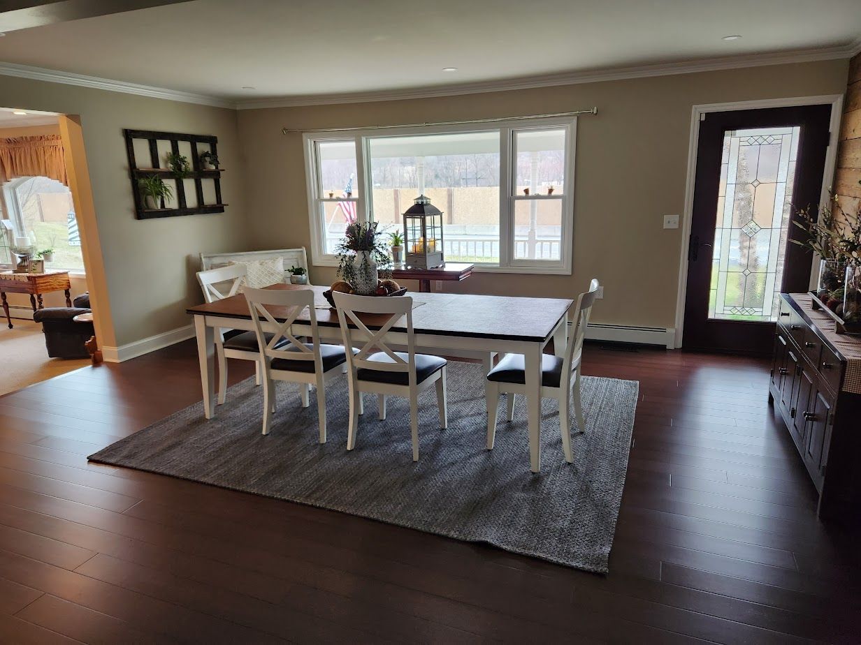 A dining room with a table and chairs and a rug.
