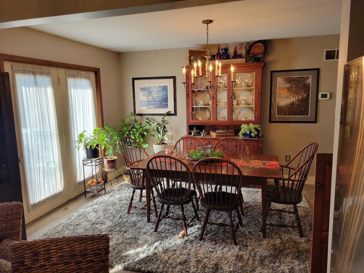 A dining room with a table and chairs and a rug.