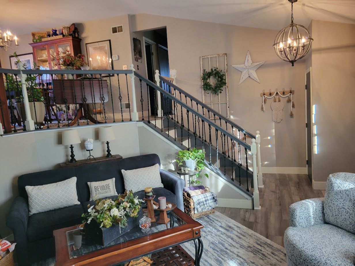 A living room with a couch , chair , coffee table and stairs.