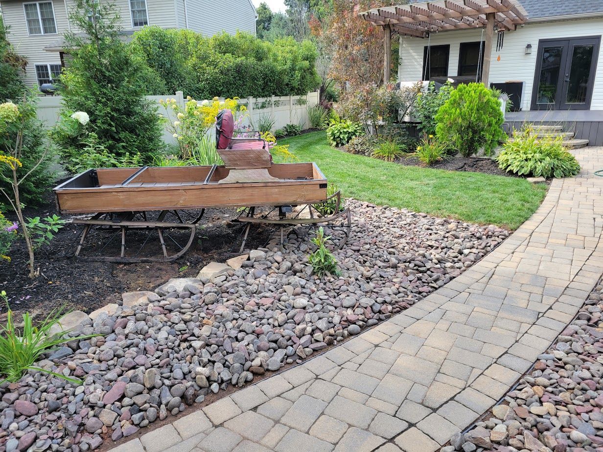 A brick walkway leading to a house with a wooden cart in the backyard.