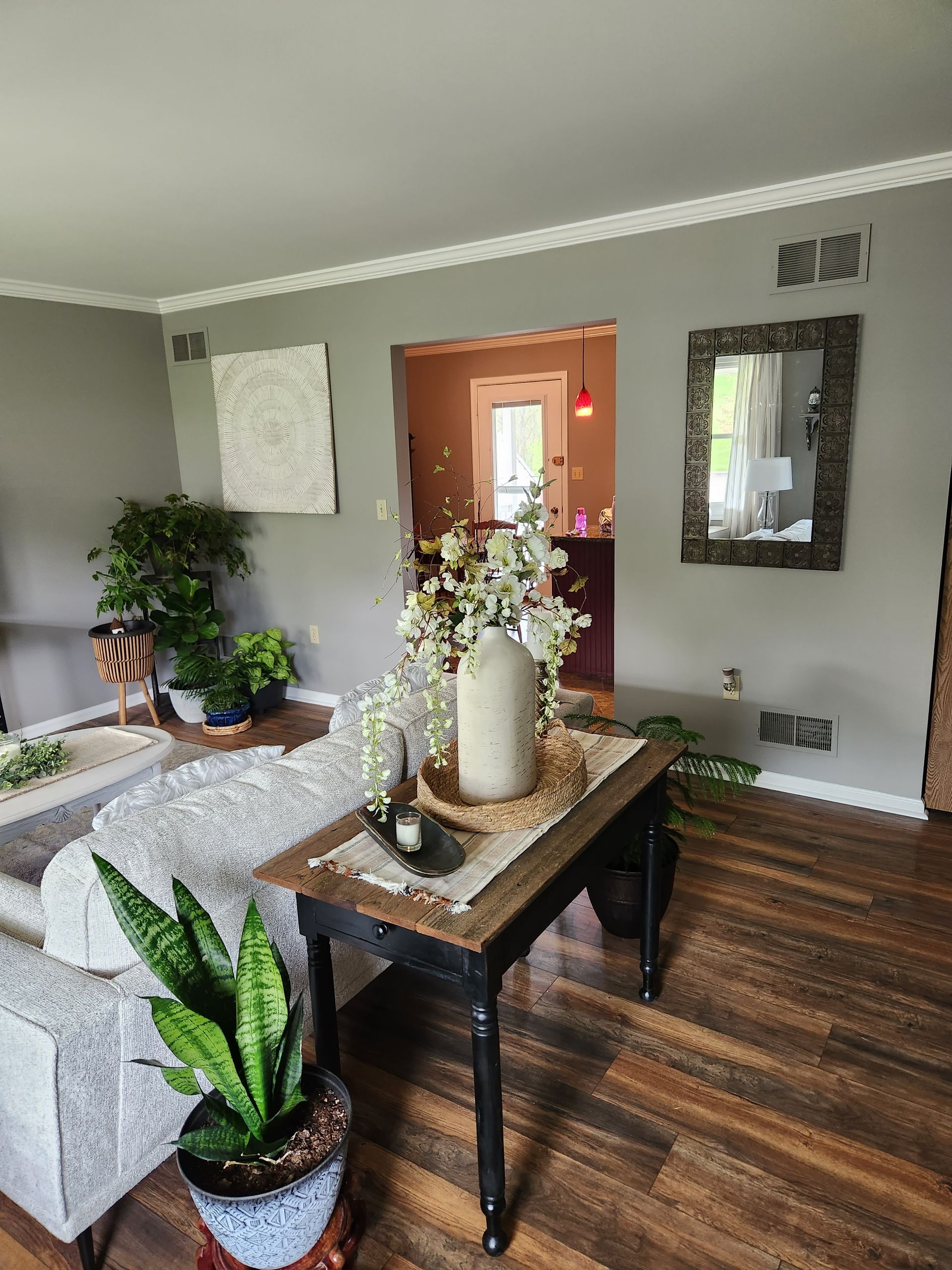 A living room with a table and a vase of flowers on it.