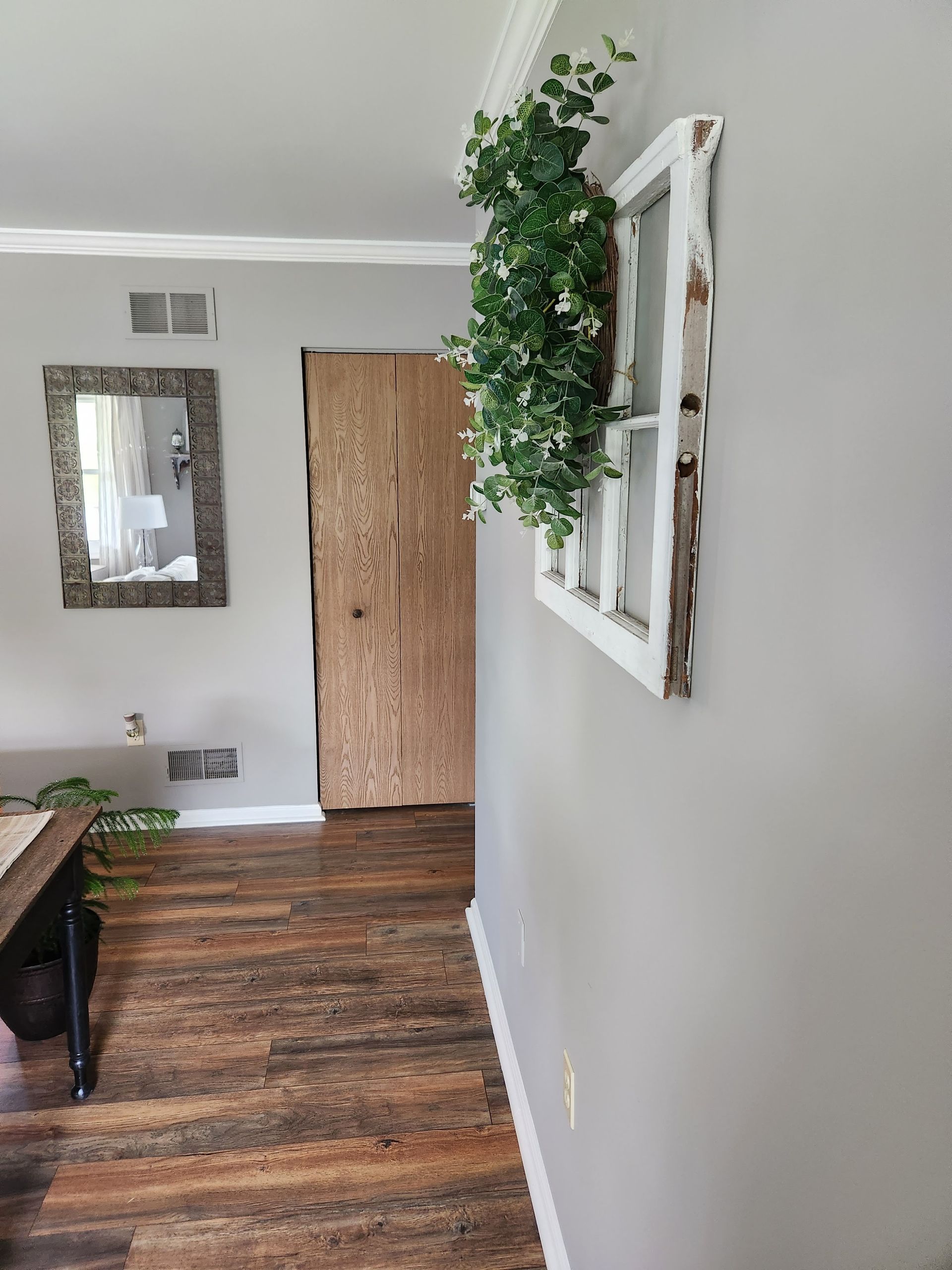 A hallway with a wooden floor and a window on the wall.